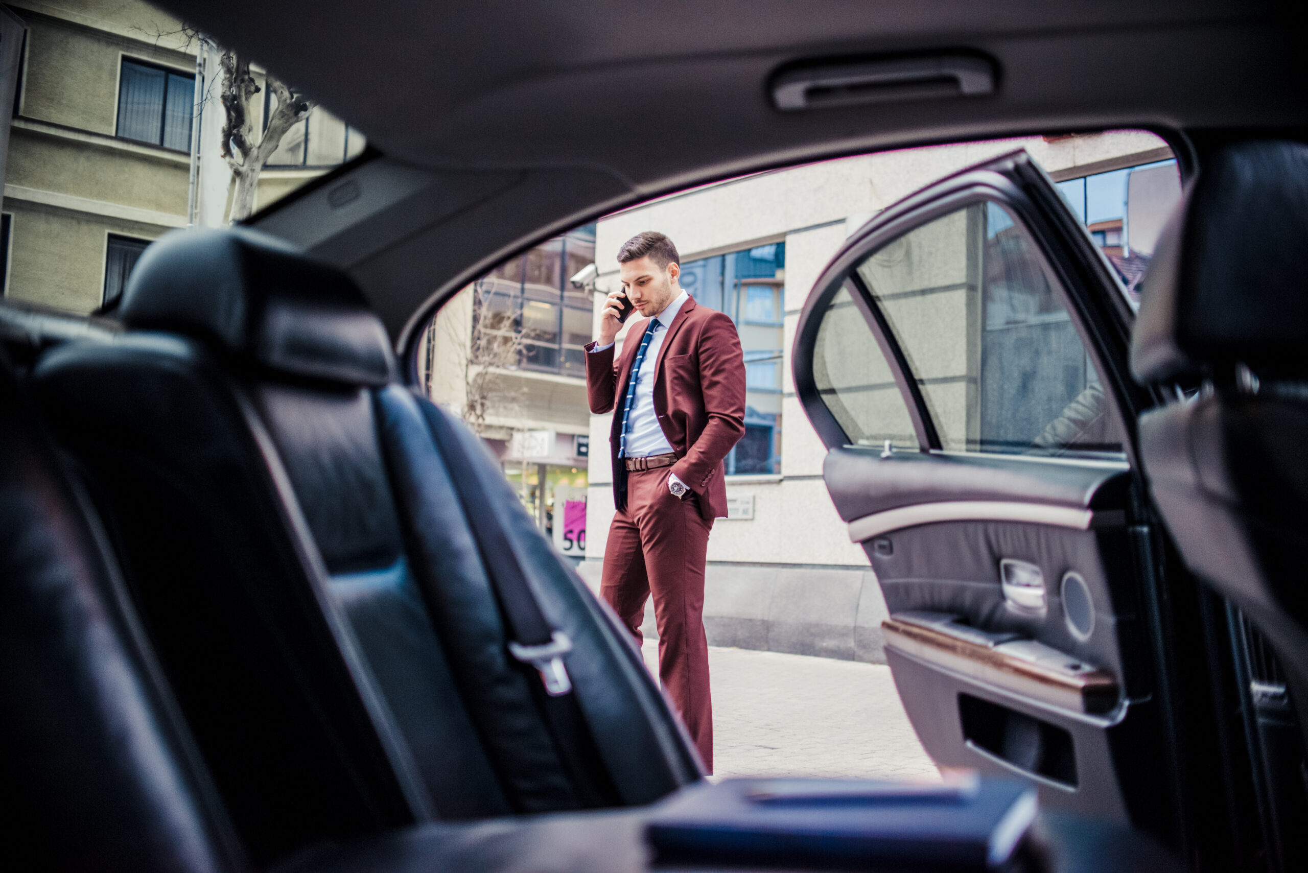 Looking out of a luxury vehicle through the open backseat door onto a man in suit